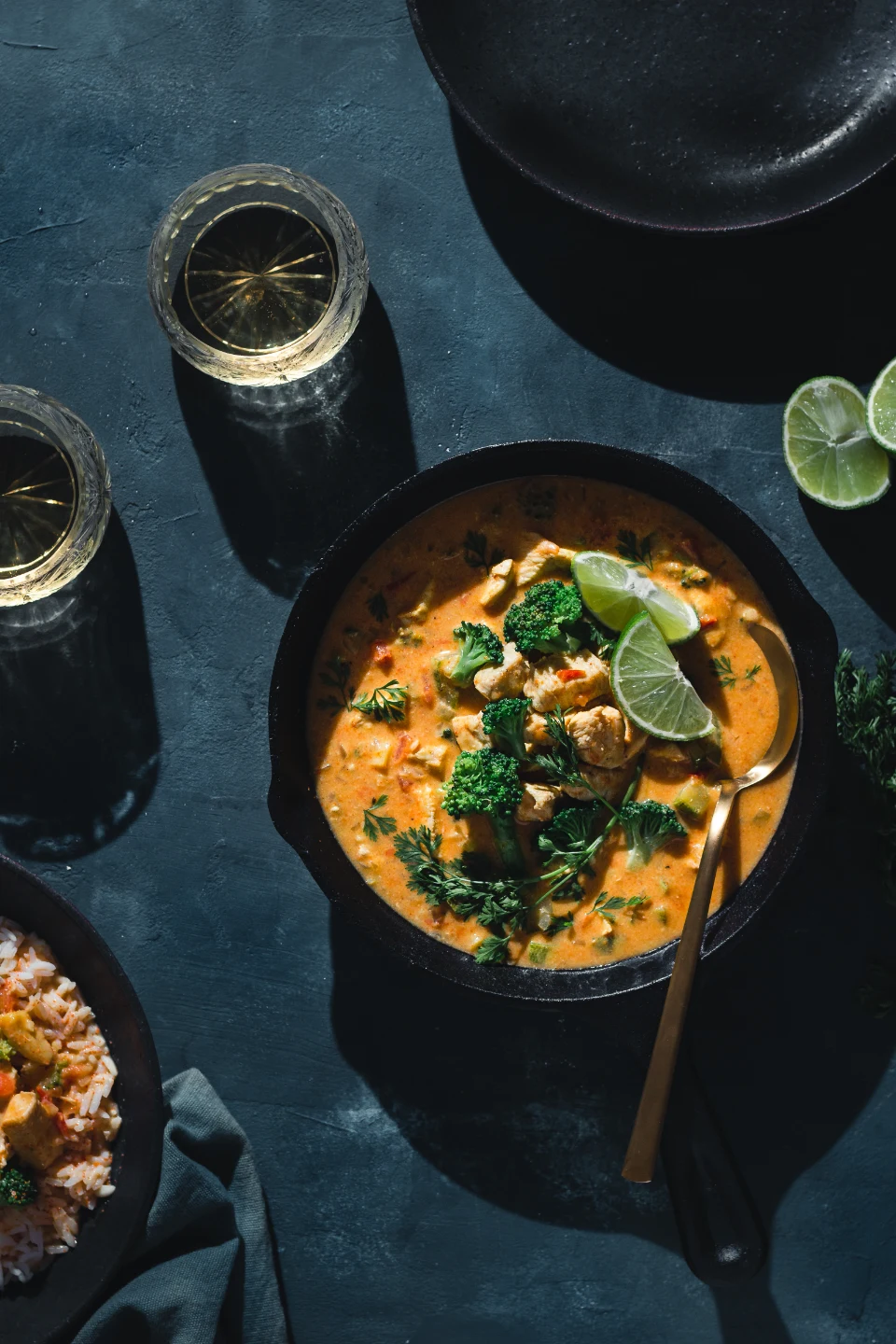 A bowl of curry topped with fresh herbs and lime